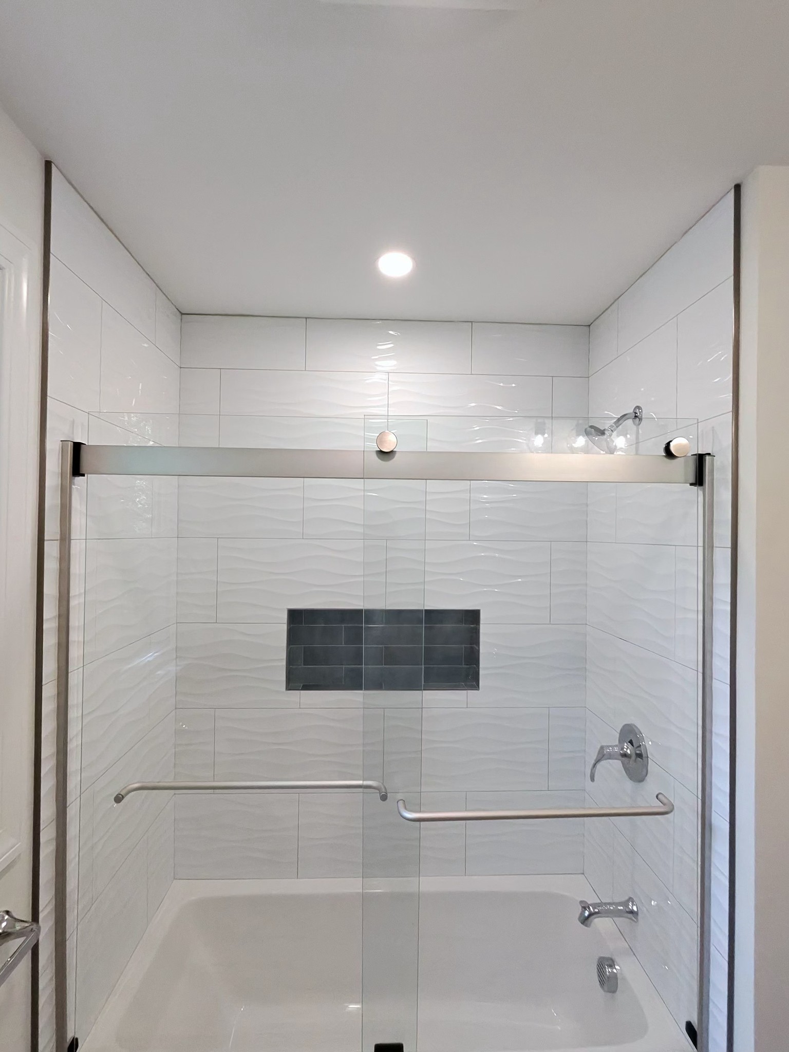 Custom tub surround, wavy white tile with slate accent niche