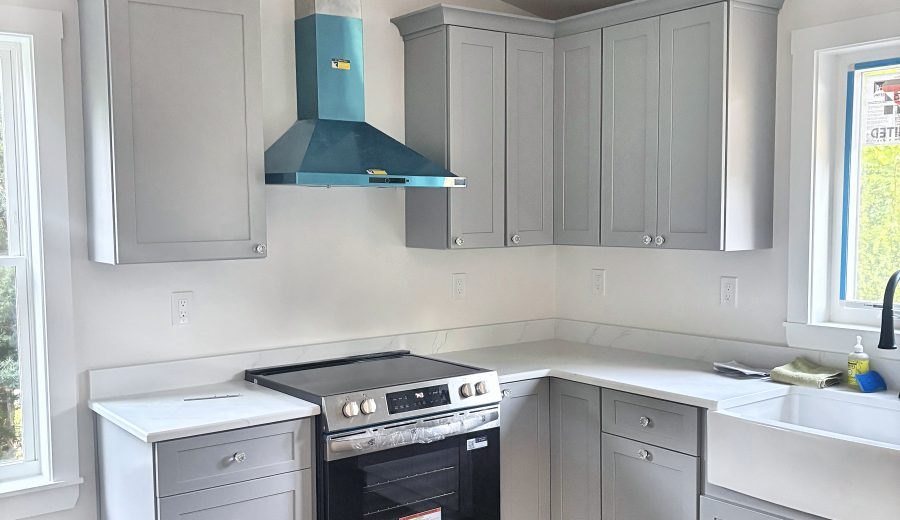 ADU kitchen — range, vented hood, dishwasher, farmhouse sink